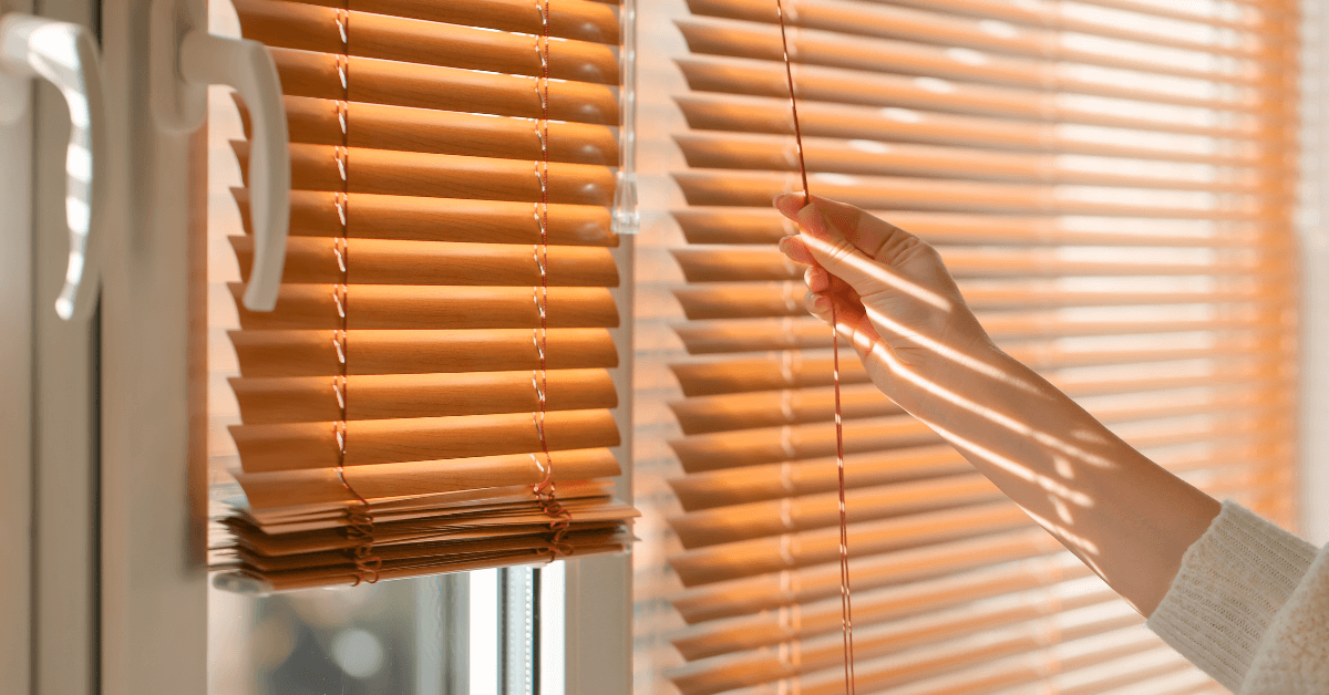 Homeowner closing blinds for summer home cooling efficiency